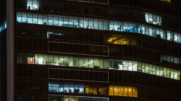 Vista de perto para janelas de escritório de arranha-céu no centro da cidade à noite, pessoas que trabalham dentro. Dubai, Emirados Árabes Unidos — Vídeo de Stock