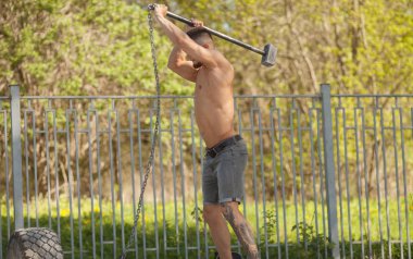 Sayısı lastiği - çekiç ile açık havada egzersiz genç adam