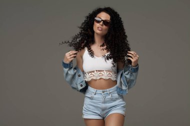 Studio moda kot poz seksi çekici esmer kadın. Moda model poz. Uzun kıvırcık saç.