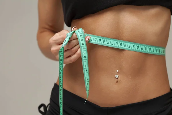 灰色の背景の上の食事後腰テープを測定測定運動にスリムな女性 — ストック写真
