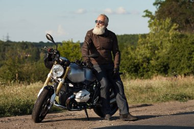 Motorcu ihtiyar bir deri ceket ve onun motosiklet üzerinde oturan güneş gözlüğü takmış.