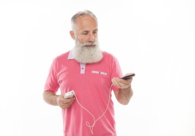 Stüdyo mutlu üst düzey sakallı adam süre şarj ve beyaz arka plan karşı cep telefonu konuşurken gülümseyen bir kadeh. Yaşlı adam şarj telefon. PowerBank.