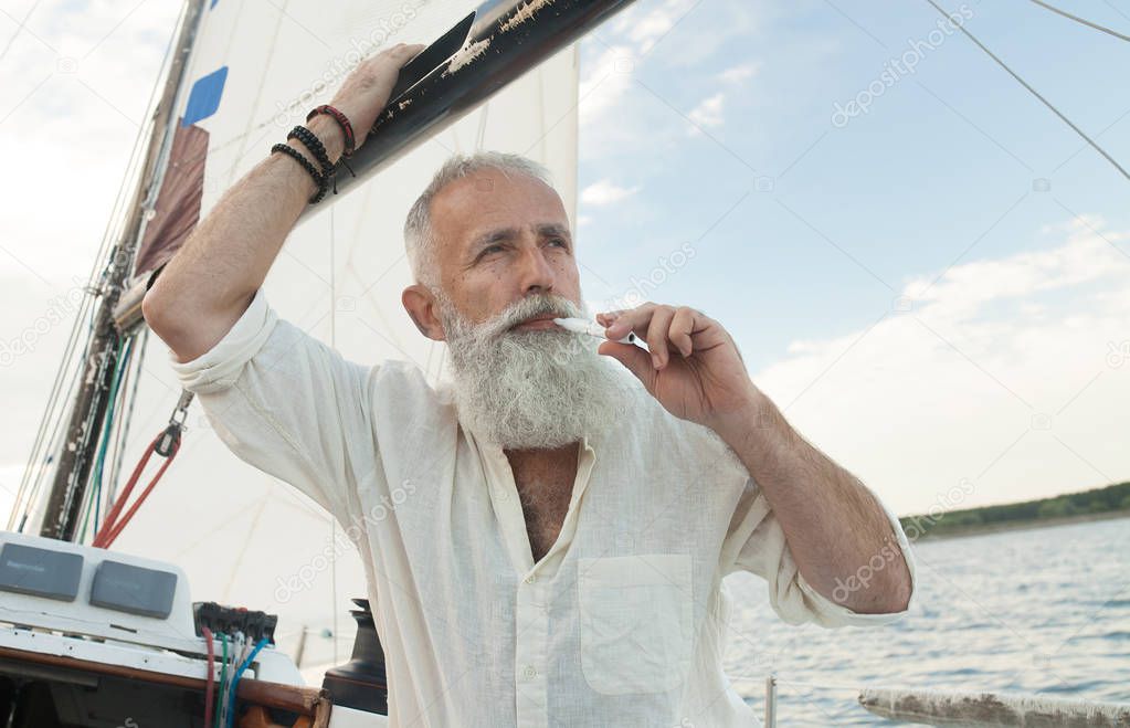 Senior Vaping, Enjoying An Electronic Cigarette. IQOS. Bearded man vape on yacht.