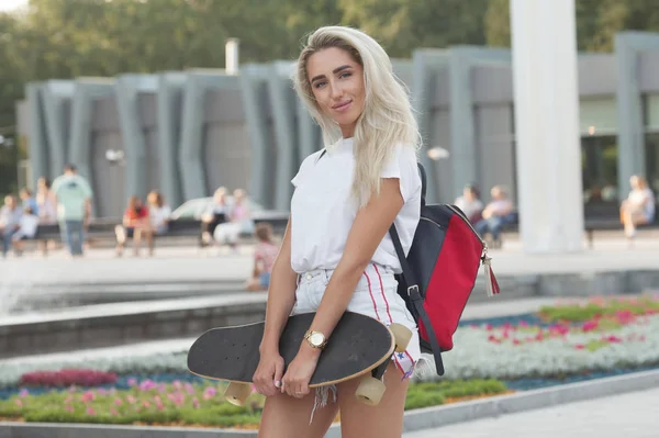 스케이트 보드와 아름다운 소녀입니다 스케이트 보드를 청바지 반바지에 여자의 보드와 — 스톡 사진