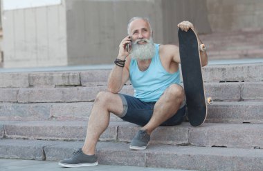 şehirde, merdivenlerde rahatlatıcı kaykay ile trendy sakallı ihtiyar