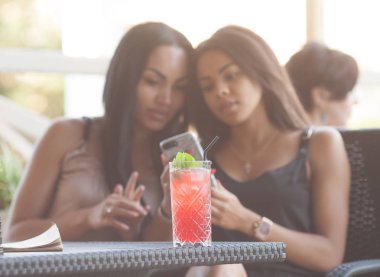 Çok ırklı kadınlar olumlu haber üstünde hareket eden telefon ile bildirimi okuyun, boş zamanlarını Teras Cafe, birbirinize sarılın, mutlu ifadeler. İki diveristy kadın bir şey Internet seçmek