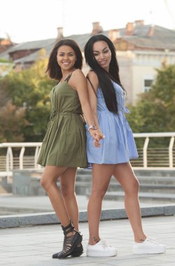 İki çok ırklı arkadaşlar açık havada portresi. Kızlar eğleniyor ve sarılma, şehirde yürüyüşe sahip rahat kıyafetler içinde alanı kopyalayın. Kentsel yaşam tarzı, dostluk kavramı