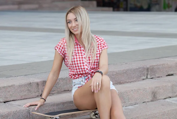 彼女のスケート ボードを持って笑顔の若い女性スケートボーダーの肖像画 見ているカメラ屋外スケート場でスケートを持つ女性ボードします — ストック写真