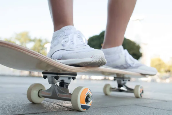Legs of a sexy woman on a wooden skateboard on the street