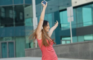 Asyalı kadın mutlu gülümseme ve telefon dinlemek müzik yaşayan kullanın