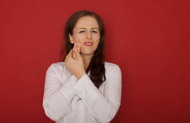 Diş sorunu. Kadın duygu diş ağrısı. Güçlü diş ağrısı acı güzel üzgün kız closeup. Çekici kadın duygu ağrılı diş ağrısı. Diş Sağlığı ve bakımı kavramı. Kırmızı zemin üzerine.
