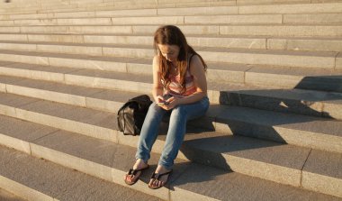 Yaz günü sokak merdivenlerde oturan ve cep telefonu tutan güzel şık kadın görüntüsünü