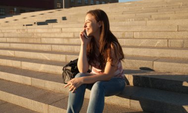 Yaz günü sokak merdivenlerde oturan ve cep telefonu tutan güzel şık kadın görüntüsünü