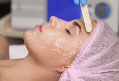 Doktor geçerlidir hidro kadının yüzünde maske jel. Lazer tedavi gören genç kadını daha önce.