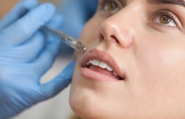 Kozmetik uzmanı hastanın dudaklarına botulinyum toksini enjekte eder. Kozmetoloji cilt bakımı.