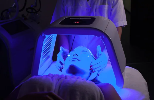 Genç kadın güzellik salonu LED ışık yüz tedavisi sahip