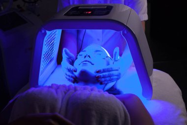 Genç kadın güzellik salonu LED ışık yüz tedavisi sahip