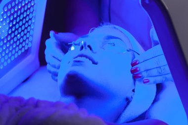Genç kadın güzellik salonu LED ışık yüz tedavisi sahip