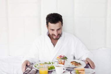 yatakta mutlu bir tek adam yemek kahvaltı