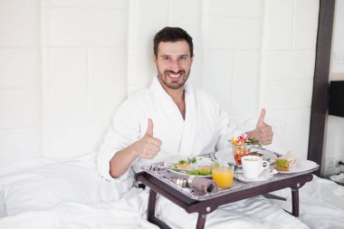 yatakta mutlu bir tek adam yemek kahvaltı