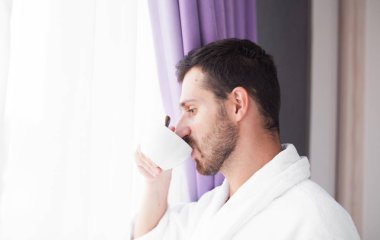 Yakışıklı esmer sakallı adam parlak pencere ve içecekler kahve önce standları