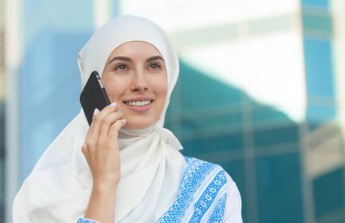 Cep telefonuyla sokakta modern bir Arap kız portresi.