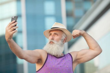 Eski etkin cep telefonu ile selfie Caddesi üzerinde alarak şapkalı adam sakallı.