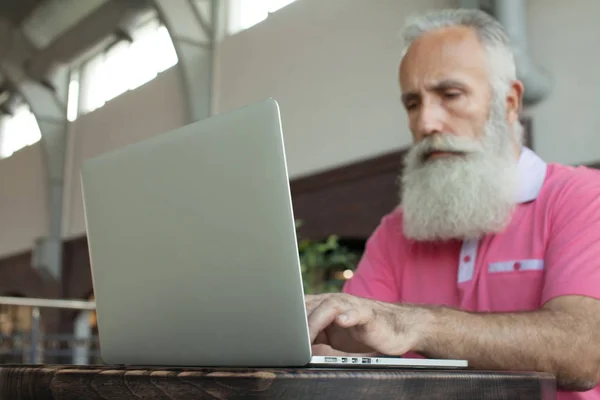 senior man looking at laptop in cafe. Old man using laptop.