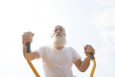 Yaşlı adam yeşil yaz park arka plan olarak karşı açık spor salonunda egzersiz yapma.