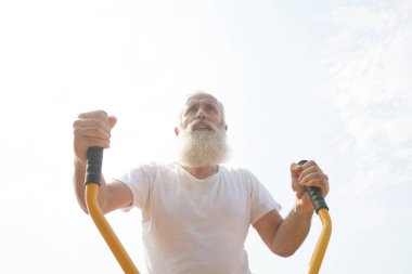 Yaşlı adam yeşil yaz park arka plan olarak karşı açık spor salonunda egzersiz yapma.