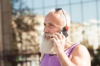 Şehir merkezinde açık - yeni eğilimleri teknoloji - Tech ve yaşlı yaşam tarzı konsepti ile eğleniyor olgun moda erkek Smartphone kullanarak trendy komuta sizde