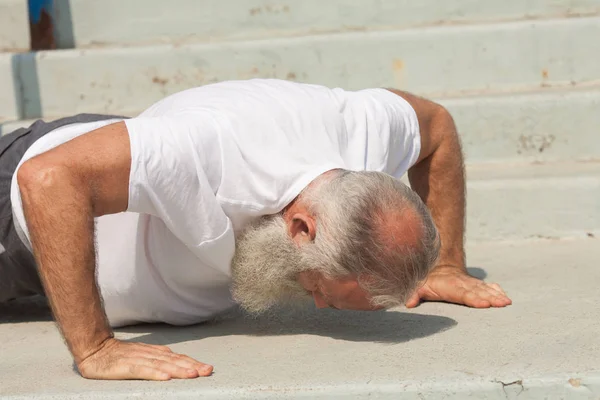 Well-built senior man doing push-ups on stairs