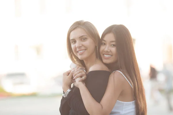 Dwie Młode Kobiety Zewnątrz Przytulanie Azjatyckie Dziewczyna Patrząc Kamery Uśmiecha — Zdjęcie stockowe