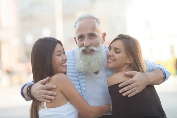 Happy Bearded Homem Sênior Abraçando Seus Jovens Amigos — Fotografia de Stock
