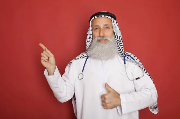 Arabischer Alter Bärtiger Krankenhausarzt Mit Stethoskop Posiert Auf Rotem Hintergrund — Stockfoto
