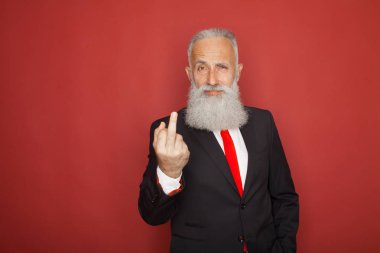 Lanet olsun kamera ve gülümseyen işaret gösteren yaşlı sakallı bir iş adamı. İş kavramı, zengin insanlar ve başarı. Kapalı, stüdyo kırmızı zemin üzerine ateş