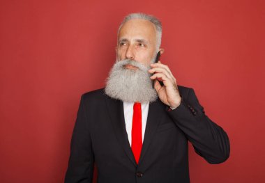 Kırmızı bir arka plan Akıllı telefon iletişim resmi elbiseli kıdemli işadamı sakallı
