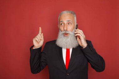Kırmızı bir arka plan Akıllı telefon iletişim resmi elbiseli kıdemli işadamı sakallı
