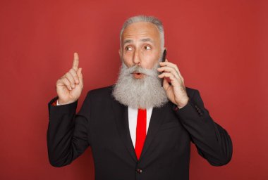 Kırmızı bir arka plan Akıllı telefon iletişim resmi elbiseli kıdemli işadamı sakallı