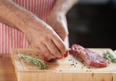 Ellerini bir adamın et ve sebze ahşap bir gemide yağsız et Dilimleme bir mutfakta hazırlanması.