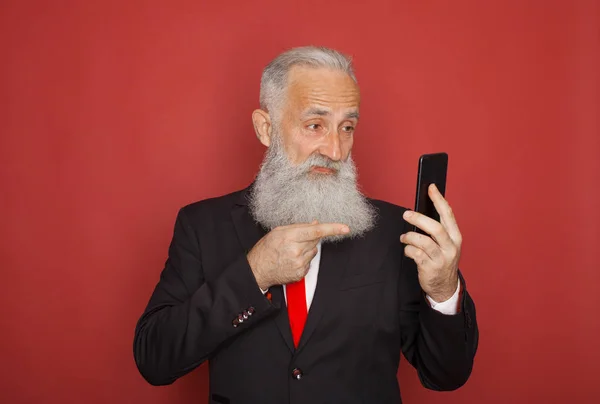 Bearded Senior Businessman in a formal suit on red background smartphone communication
