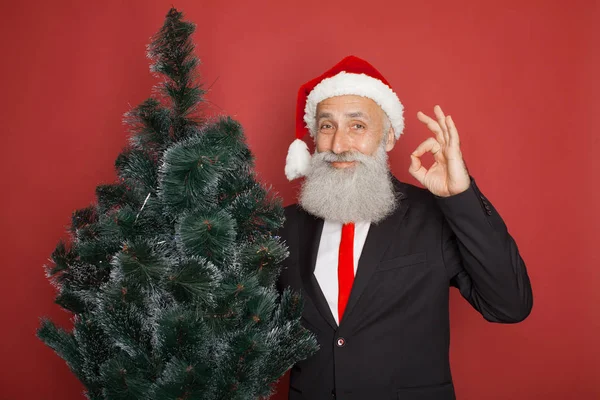 Senior Szakállas Üzletember Santa Kalap Piros Háttéren Karácsonyfa — Stock Fotó