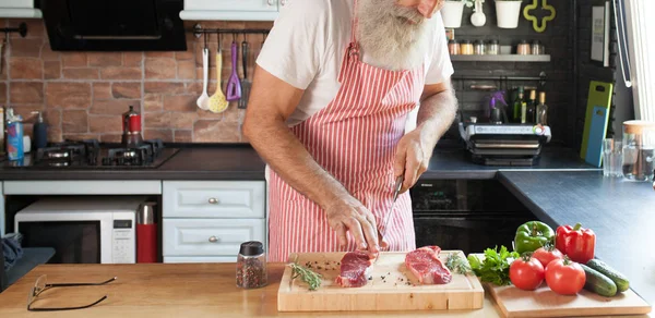 Bebaarde Senior Man Steaks Zijn Keuken Koken — Stockfoto