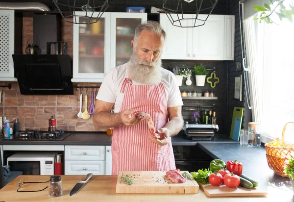 Bebaarde Senior Man Steaks Zijn Keuken Koken — Stockfoto