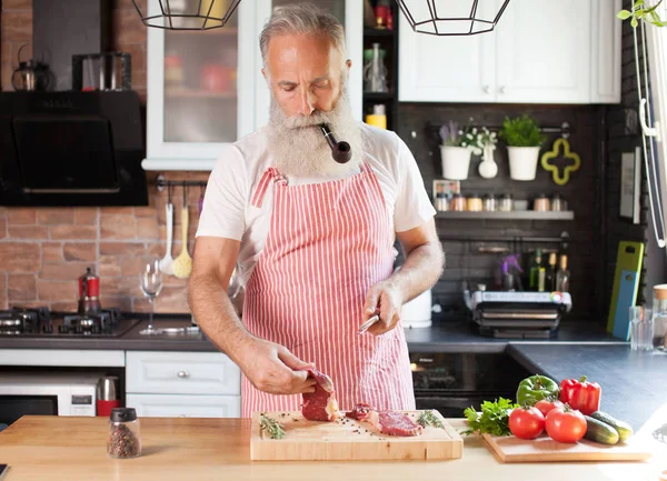 Bebaarde Senior Man Steaks Zijn Keuken Koken — Stockfoto