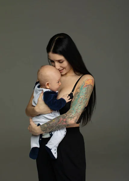 Anne Gri Arka Planda Kollarında Bebek Tutar — Stok fotoğraf