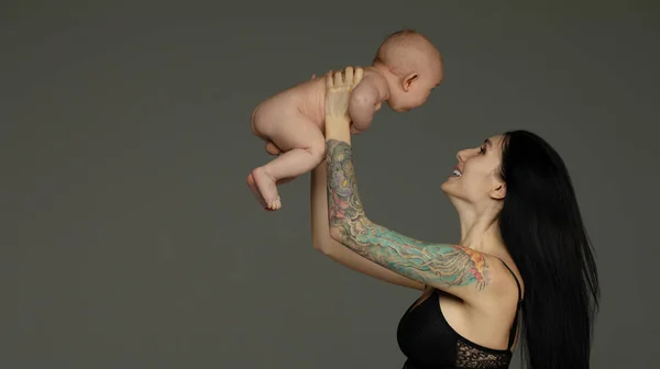 Madre Sostiene Bebé Sus Brazos Sobre Fondo Gris —  Fotos de Stock