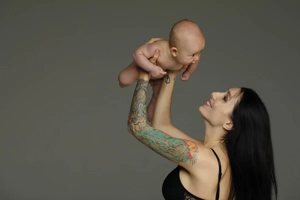 Madre Sostiene Bebé Sus Brazos Sobre Fondo Gris — Foto de Stock