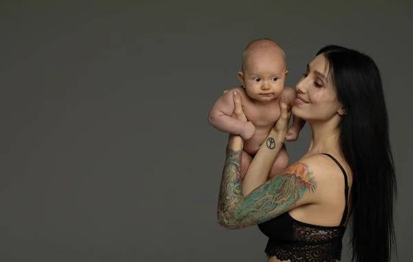 Madre Sostiene Bebé Sus Brazos Sobre Fondo Gris —  Fotos de Stock