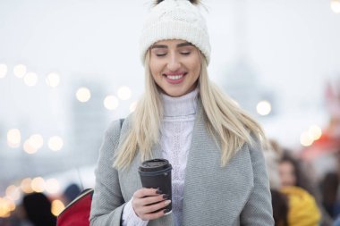 Sevimli kız sırt çantası ile ceket sokakta yürüyüş büyük şehirde mutlu kış zamanı. Kar yağışının keyfini çıkarmak, pozitifliği ifade etmek, kameraya gülümsemek, neşeli neşeli ruh hali, gerçek duygular, yeni yıl havası